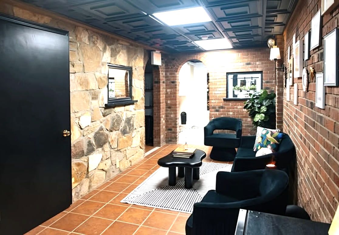 Waiting room with brick and stone walls, black chairs, black door